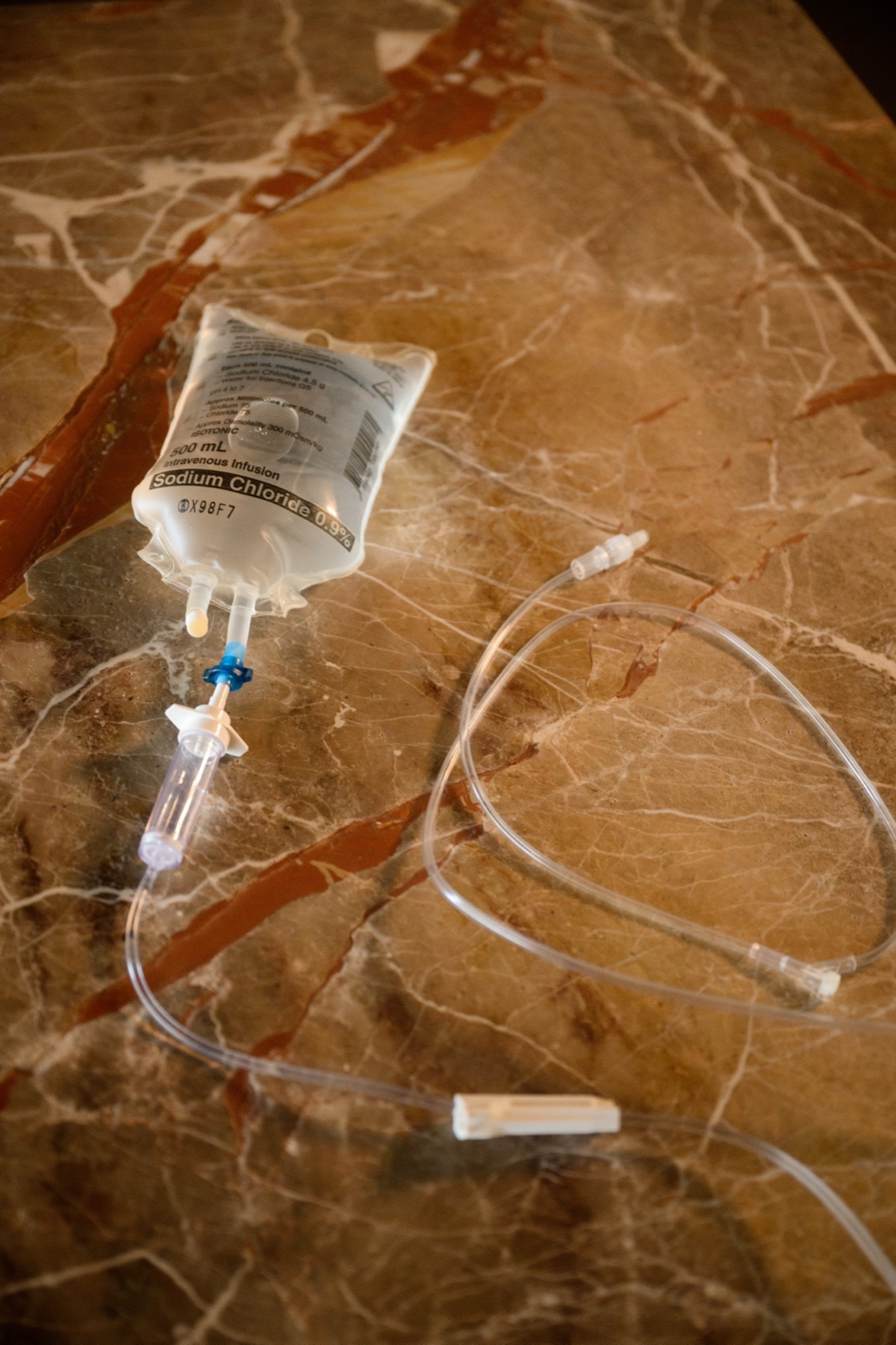 An IV saline bag and tubing arranged on warm stone