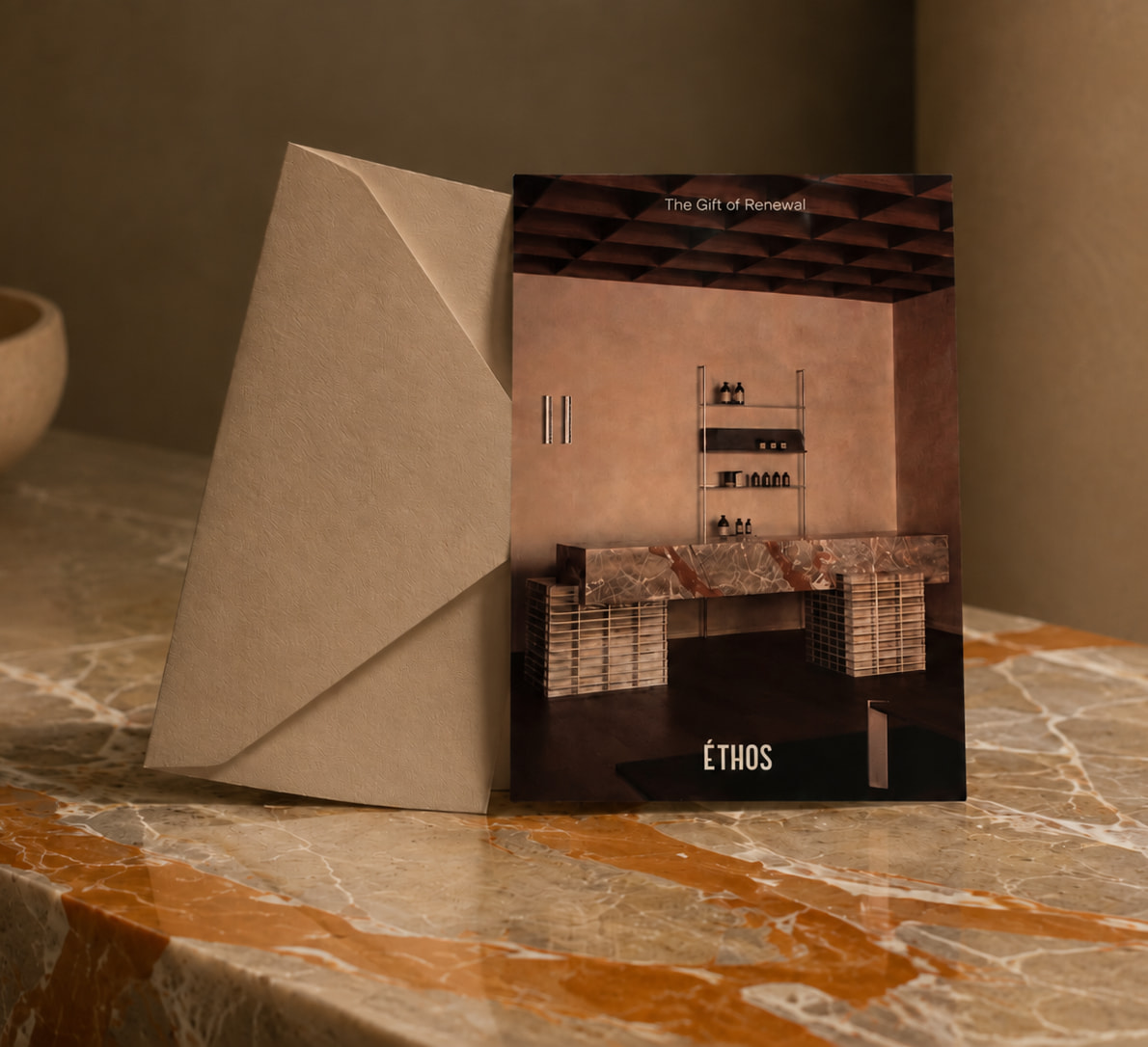 An Éthos gift card and presentation envelope on warm stone