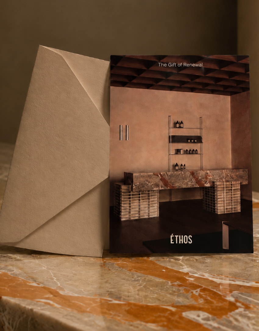 An Éthos gift card and presentation envelope on warm stone