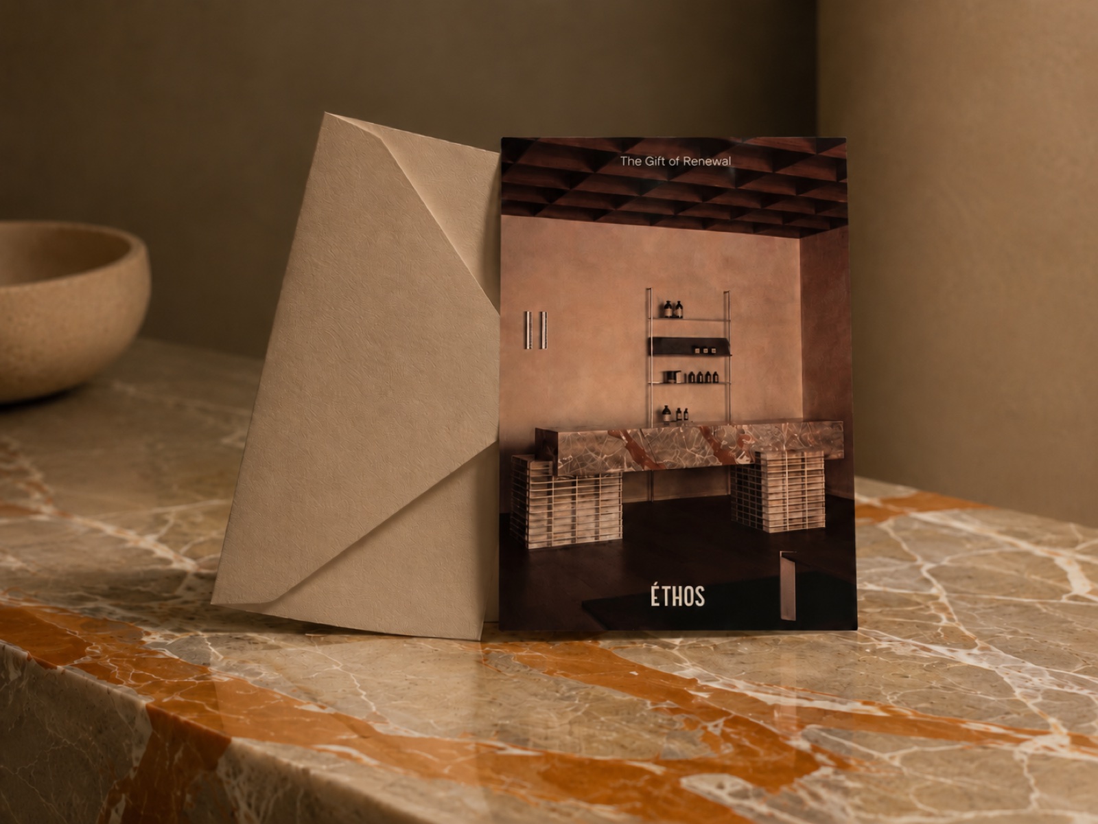 An Éthos gift card and presentation envelope on warm stone